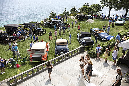 Concours event guests on back porch and vintage cars on the Misselwood back lawn